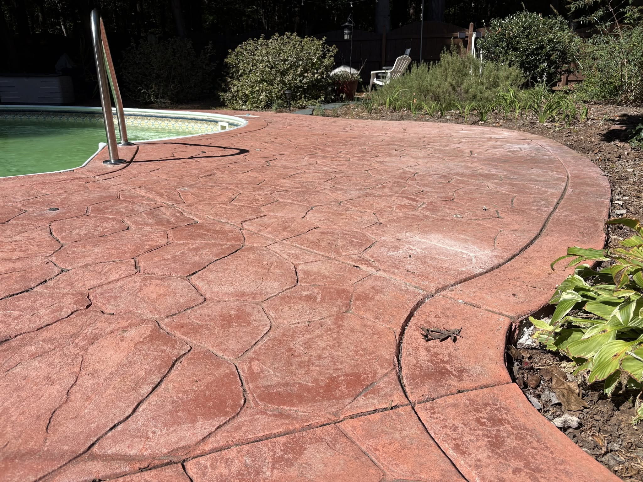 Cracked, settled stamped concrete pool deck before lifting